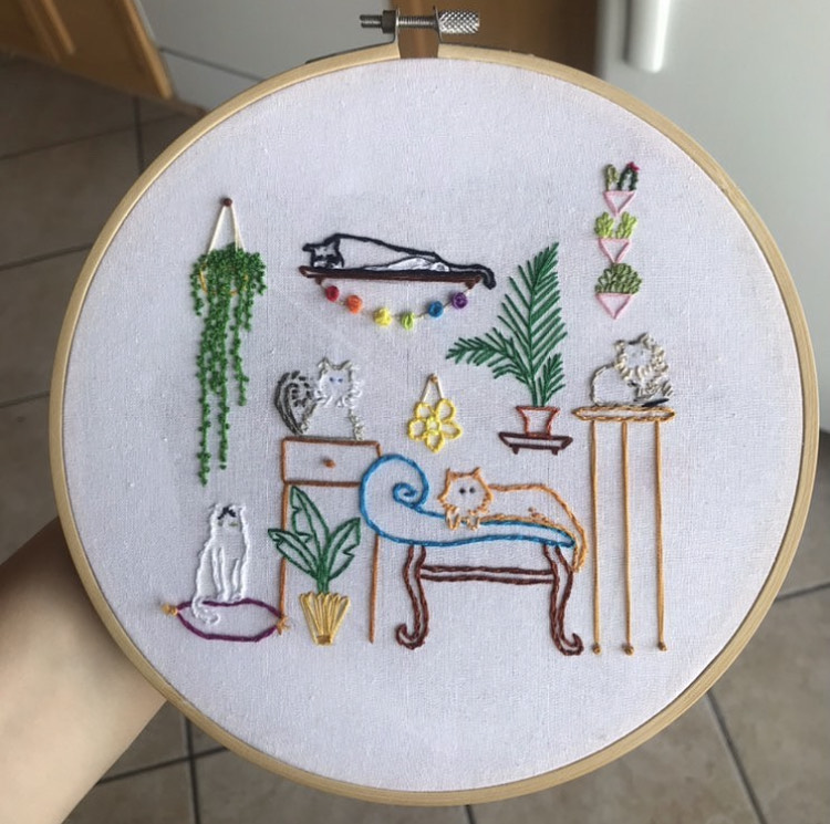 hoop embroidery; five cats are lounging around in a bright and colourful indoor landscape, decorated with plants.
